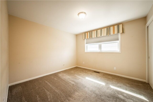 carpeted empty room featuring visible vents and baseboards