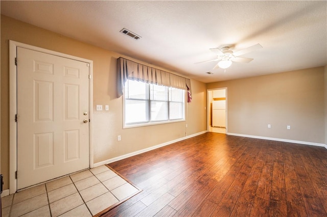 foyer entrance featuring visible vents, ceiling fan, baseboards, and wood finished floors