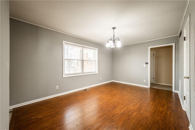 spare room with a chandelier, dark wood-type flooring, visible vents, and baseboards