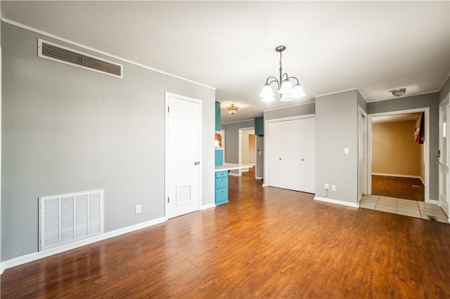 empty room featuring visible vents, a notable chandelier, and wood finished floors