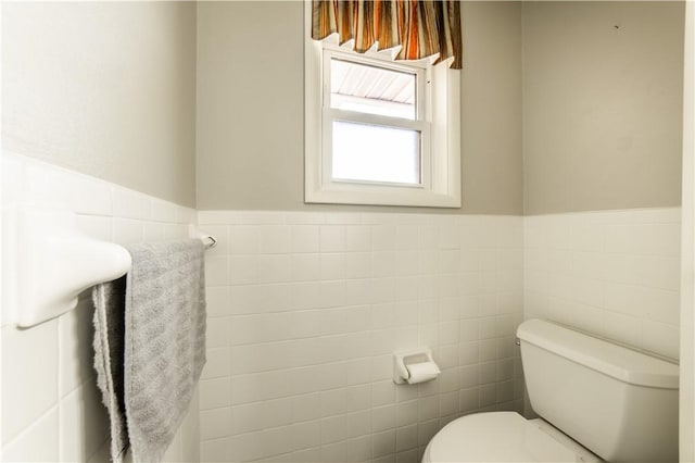 bathroom with a wainscoted wall, tile walls, and toilet