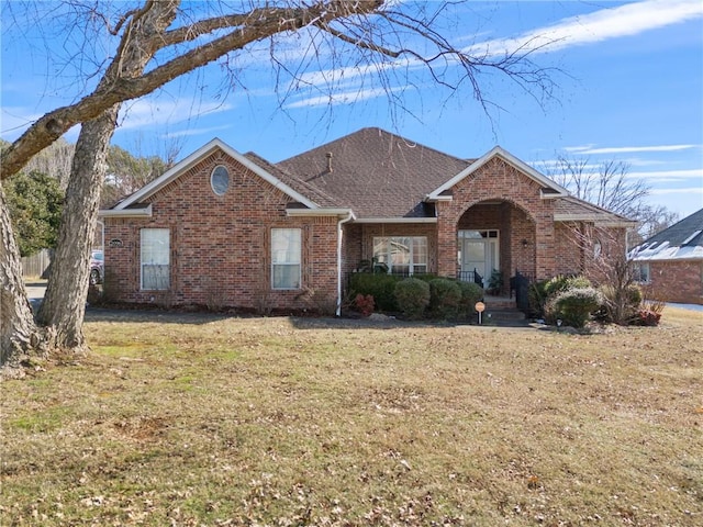 ranch-style house featuring brick siding, roof with shingles, and a front yard