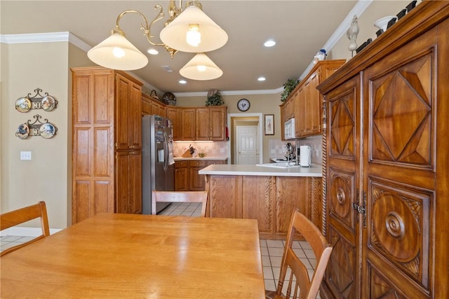 kitchen with white microwave, light tile patterned flooring, backsplash, stainless steel fridge, and crown molding