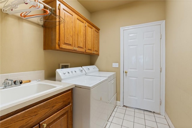 laundry area featuring washer and clothes dryer, light tile patterned floors, cabinet space, a sink, and baseboards