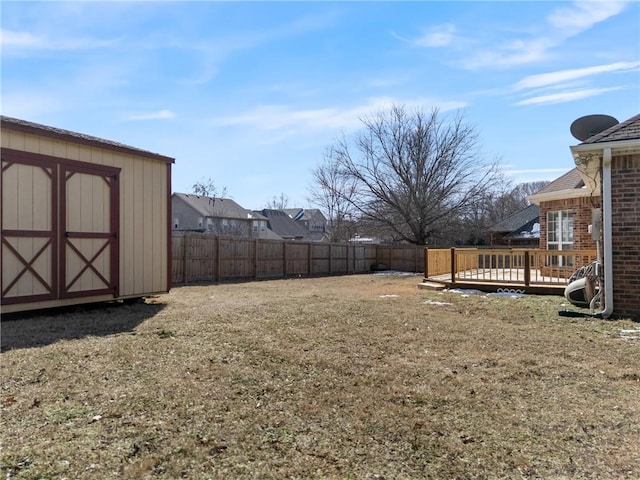 view of yard with a fenced backyard, an outdoor structure, a deck, and a storage shed