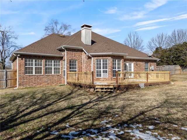 rear view of house featuring a yard, a chimney, fence, and brick siding