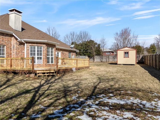 view of yard featuring a fenced backyard, an outdoor structure, a wooden deck, and a storage unit