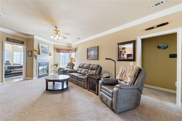 carpeted living room featuring ceiling fan, a fireplace, visible vents, baseboards, and ornamental molding