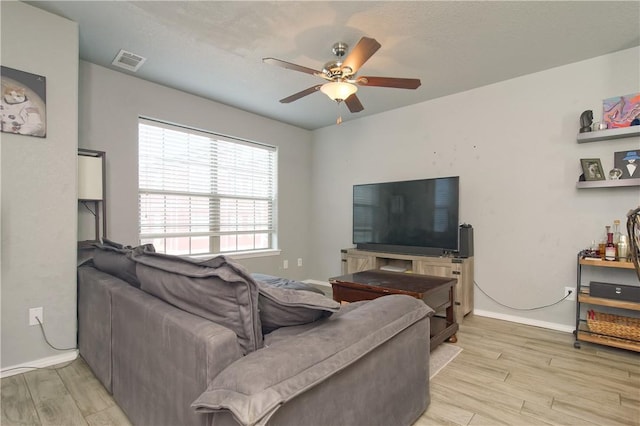 living area with light wood-style floors, visible vents, ceiling fan, and baseboards