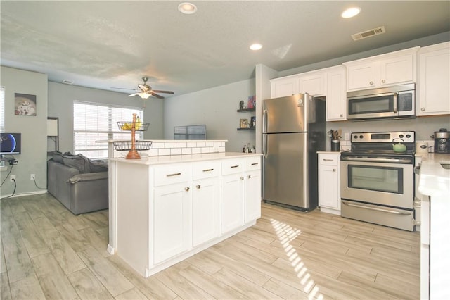 kitchen with visible vents, appliances with stainless steel finishes, open floor plan, light countertops, and wood finish floors