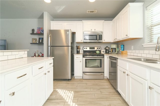 kitchen featuring white cabinetry, visible vents, stainless steel appliances, and a sink