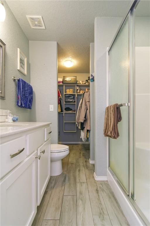 full bath featuring visible vents, wood finished floors, a textured ceiling, vanity, and a shower stall