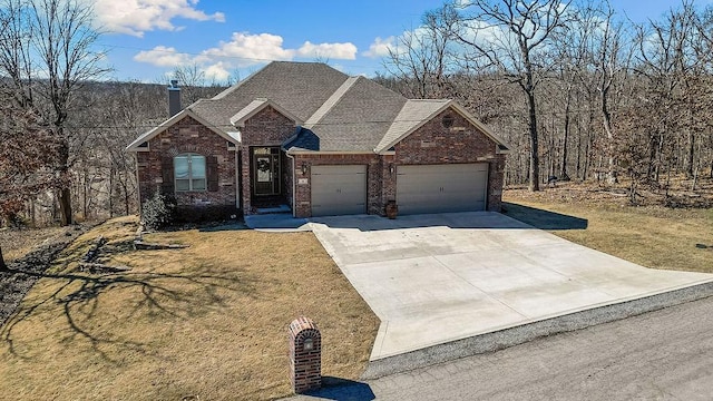 view of front of property featuring brick siding, a front lawn, concrete driveway, and a garage