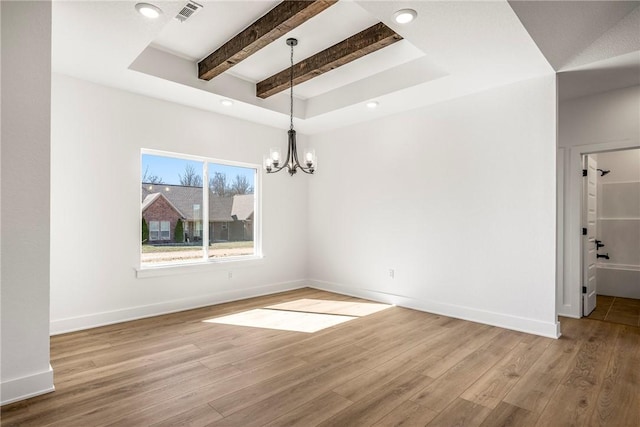 empty room with wood finished floors, visible vents, and baseboards