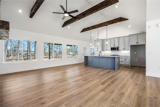 kitchen featuring stainless steel microwave, gray cabinetry, a ceiling fan, light wood-type flooring, and baseboards