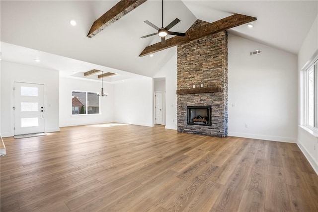 unfurnished living room featuring a stone fireplace, beamed ceiling, wood finished floors, and visible vents