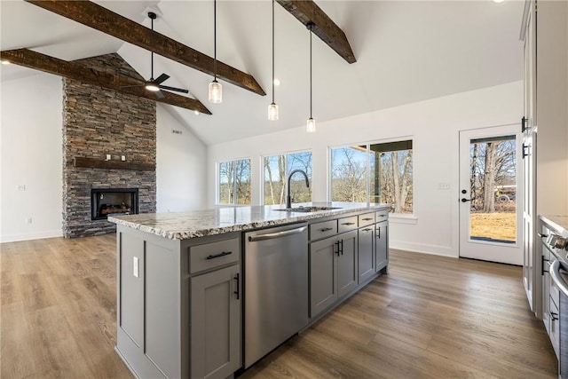 kitchen with a sink, light stone counters, gray cabinets, and stainless steel dishwasher