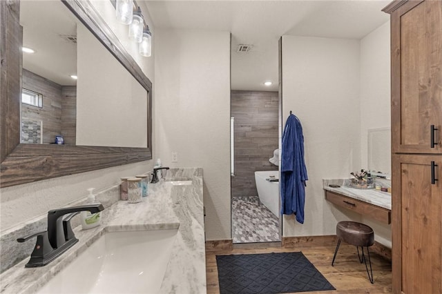 bathroom featuring a tile shower, wood finished floors, and a sink