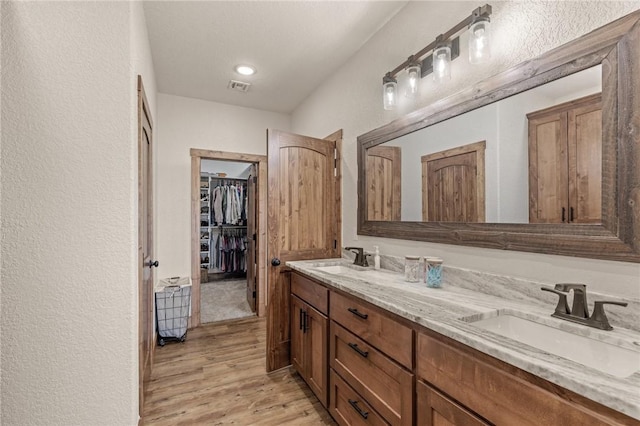 bathroom with double vanity, visible vents, a sink, and wood finished floors