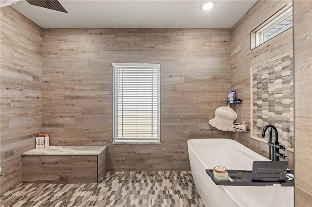 full bath featuring a freestanding tub, a healthy amount of sunlight, and a tile shower