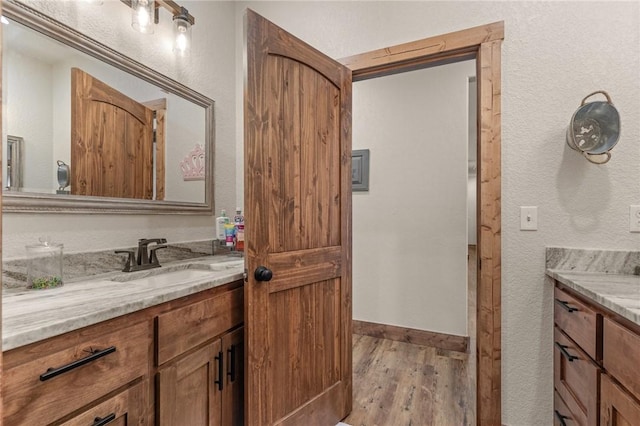 bathroom with baseboards, wood finished floors, and vanity