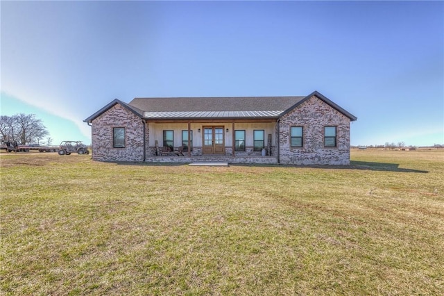 view of front of home featuring french doors, brick siding, and a front lawn