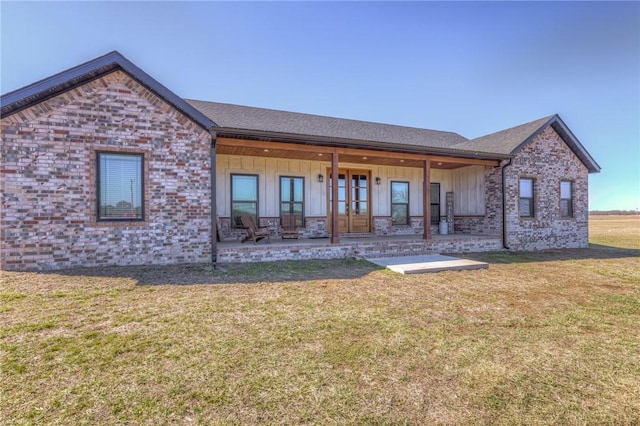 rear view of property with a lawn, a patio, french doors, board and batten siding, and brick siding