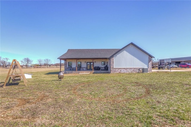 view of front of home featuring french doors, a front lawn, board and batten siding, and stone siding