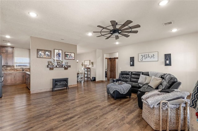 living room with dark wood-style floors, recessed lighting, visible vents, a barn door, and ceiling fan