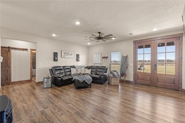 living room with wood finished floors, a textured ceiling, french doors, and a barn door