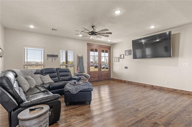 living room featuring a textured ceiling, french doors, wood finished floors, and visible vents