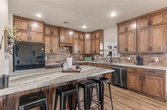 kitchen with tasteful backsplash, a breakfast bar, a sink, and stainless steel dishwasher