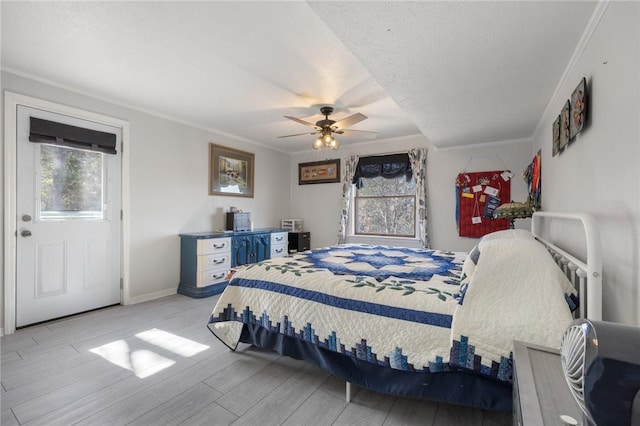 bedroom with ceiling fan, a textured ceiling, wood finished floors, baseboards, and ornamental molding