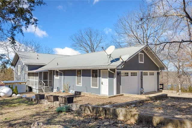 view of front of home featuring an attached garage, a sunroom, and metal roof