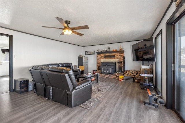 living room with a textured ceiling, wood finished floors, a ceiling fan, and crown molding