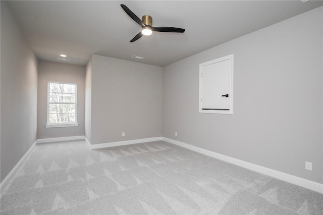 spare room with light carpet, ceiling fan, and baseboards