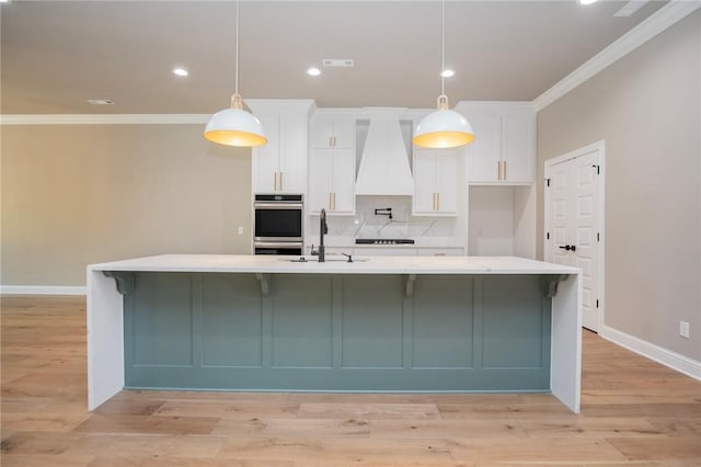 kitchen with a sink, white cabinets, and crown molding