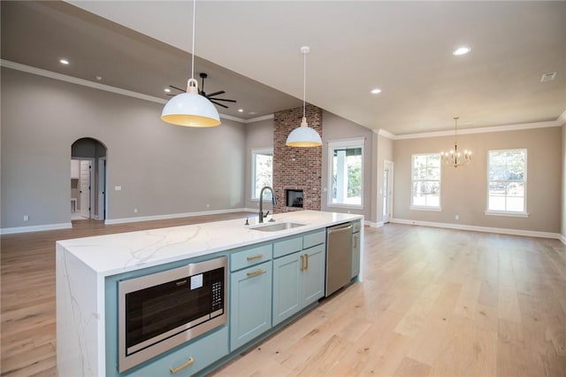 kitchen featuring a brick fireplace, open floor plan, a sink, built in microwave, and dishwasher