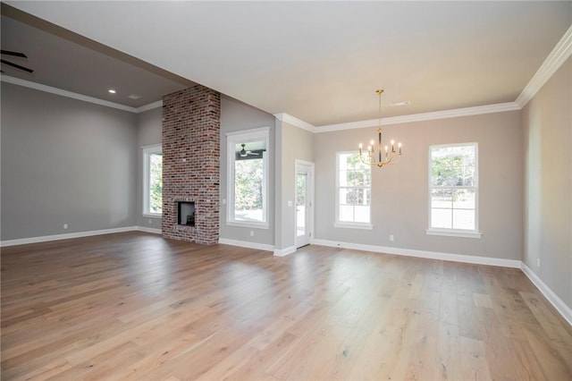 unfurnished living room with ceiling fan with notable chandelier, a fireplace, light wood-style flooring, and plenty of natural light