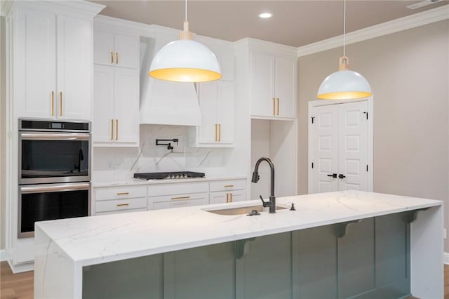 kitchen with double oven, white cabinetry, decorative backsplash, and a sink