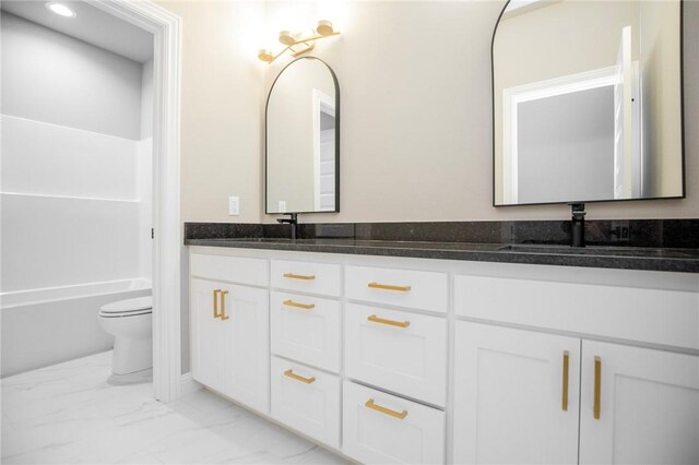 full bath featuring marble finish floor, a sink, toilet, and double vanity