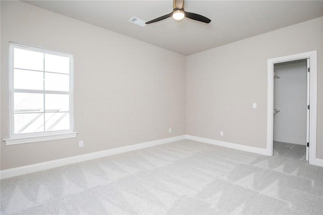 unfurnished room with baseboards, ceiling fan, visible vents, and light colored carpet