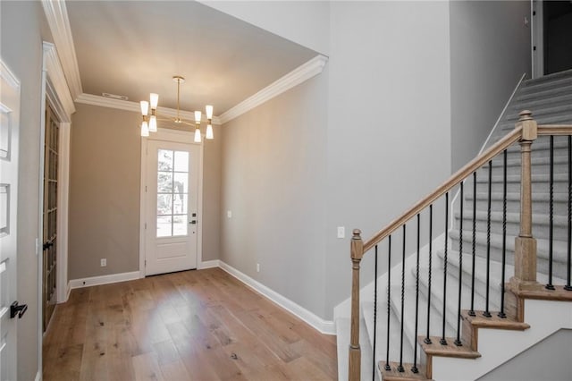 entryway with baseboards, a notable chandelier, wood finished floors, and crown molding