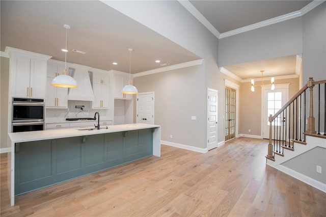 kitchen featuring white cabinets, light wood-style floors, custom range hood, and light countertops