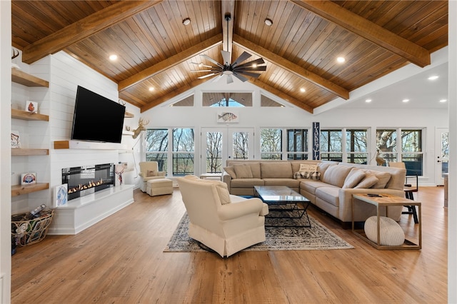 living room with light wood-style floors, a fireplace, high vaulted ceiling, and beamed ceiling