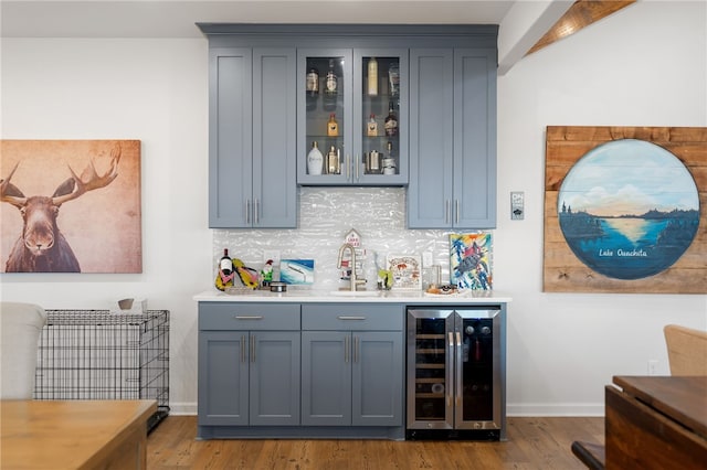 bar featuring beverage cooler, decorative backsplash, indoor wet bar, and wood finished floors