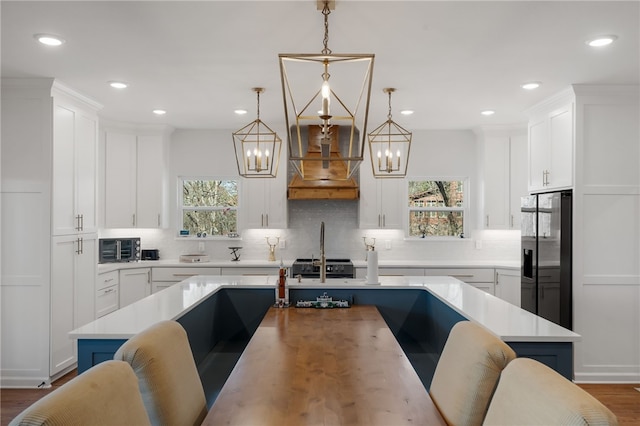 kitchen featuring a healthy amount of sunlight, refrigerator with ice dispenser, light countertops, and decorative light fixtures