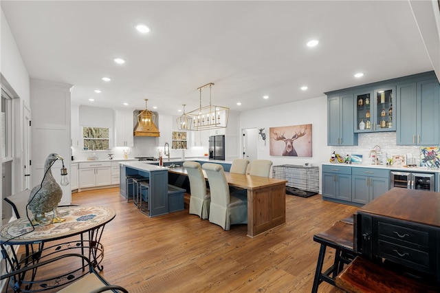 kitchen featuring light wood finished floors, wine cooler, blue cabinets, light countertops, and stainless steel refrigerator with ice dispenser