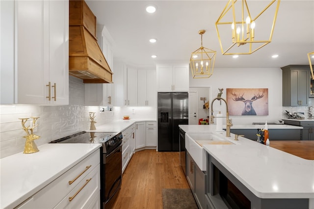 kitchen featuring light wood-style flooring, premium range hood, fridge with ice dispenser, light countertops, and black range with electric cooktop