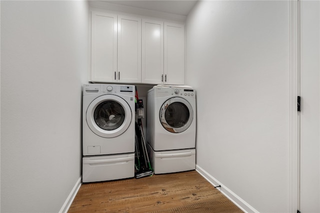 laundry room with light wood-type flooring, independent washer and dryer, cabinet space, and baseboards